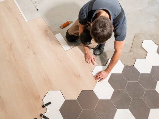 flooring installer combining ceramic and wood flooring in a modern pattern