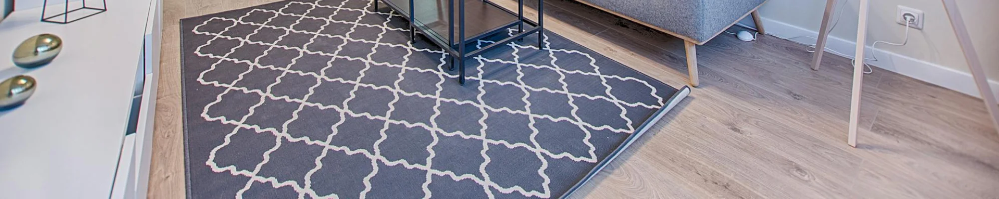 room with a grey couch, geometrical area run and vinyl flooring
